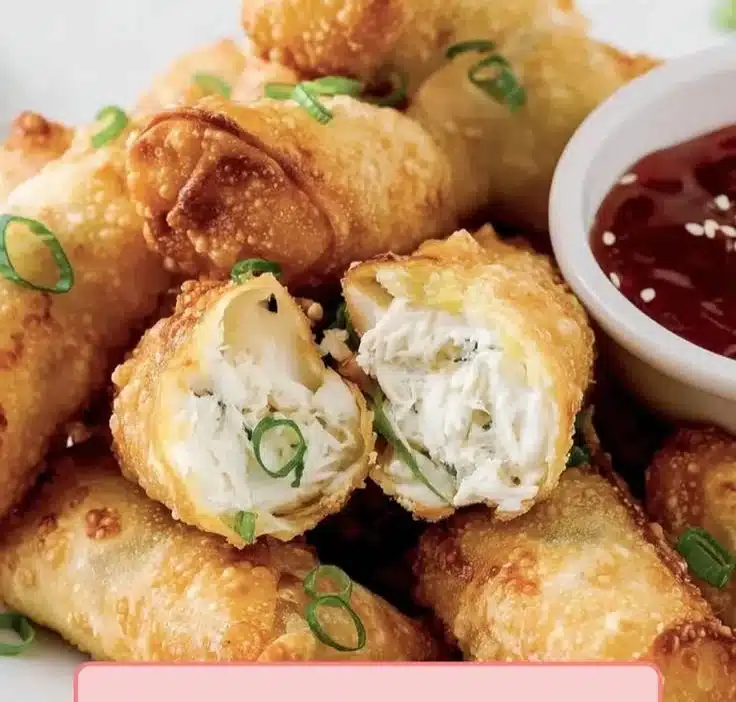Crispy crab cream cheese egg rolls on a plate garnished with dipping sauce