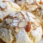Italian Almond Ricotta Cookies on a plate with almonds and flour in the background.